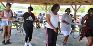 Three women dancing under a pavilion at a park.